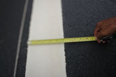 High angle view of hand measuring marking on road