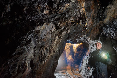 Man with illuminated headlamp standing in cave