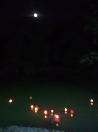 Defocused image of illuminated lights against sky at night