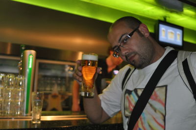 Portrait of man holding glass while standing at home