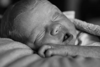 Close-up of baby sleeping on bed at home