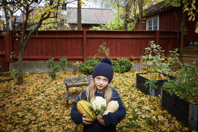 Portrait of girl holding freshly produce vegetables in garden