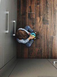 Directly above shot of boy playing with toy on hardwood floor at home