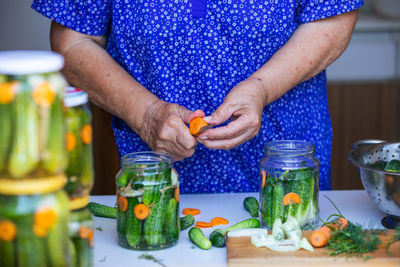 Process of canning a cucumber, senior woman canning fresh cucumbers with onion and carrots