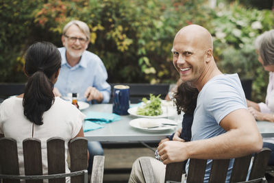 Side view portrait of happy man enjoying meal with family at outdoor table