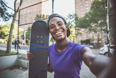 Portrait of smiling young man using mobile phone in city