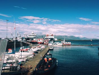 Boats moored at harbor against sky