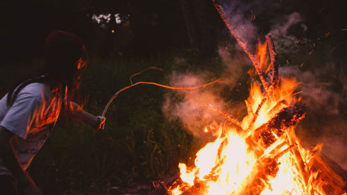 Side view of woman burning sticks in forest