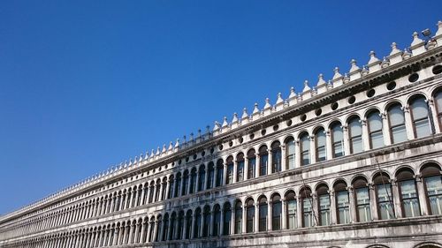 Low angle view of buildings against clear blue sky on sunny day at piazza san marco