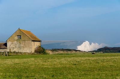 Farm building at seaford head, south downs, against distant seven sisters white cliffs, east sussex