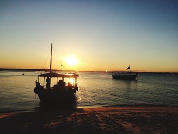 Silhouette boat at lakeshore against sky during sunset