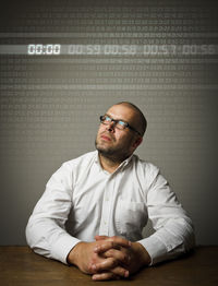 Portrait of man sitting on table against wall