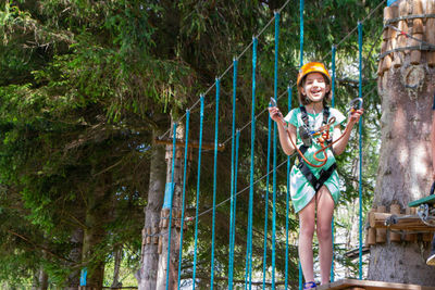 Adventure climbing high wire park - people on course in mountain helmet and safety equipment