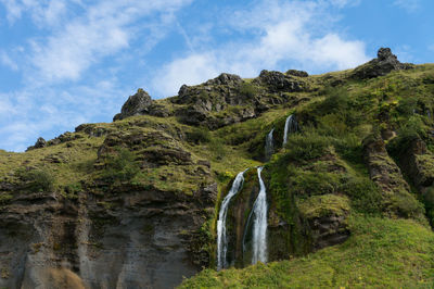 Idyllic shot of water fall on mountain against sky