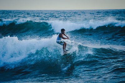 Man surfing in sea against sky