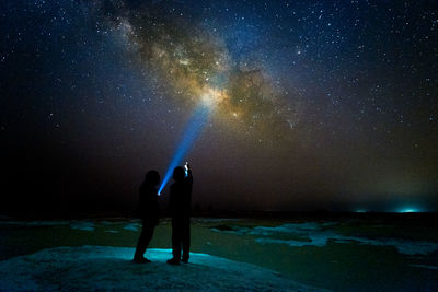 Full length of silhouette people on field against star field at night