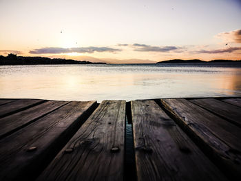 Pier over lake against sky during sunset