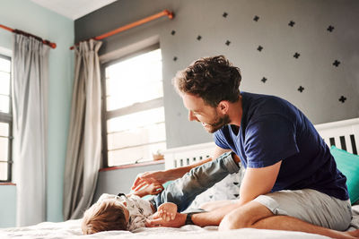 Father playing with son on bed at home