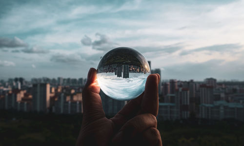 Person holding lens ball against cityscape