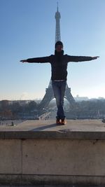 Portrait of man with arms outstretched against sky