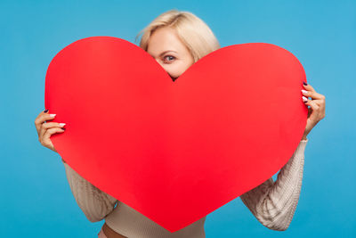 Midsection of woman holding heart shape against gray background