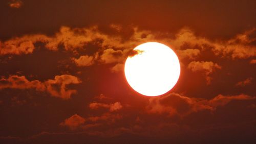 Low angle view of sun shining through clouds