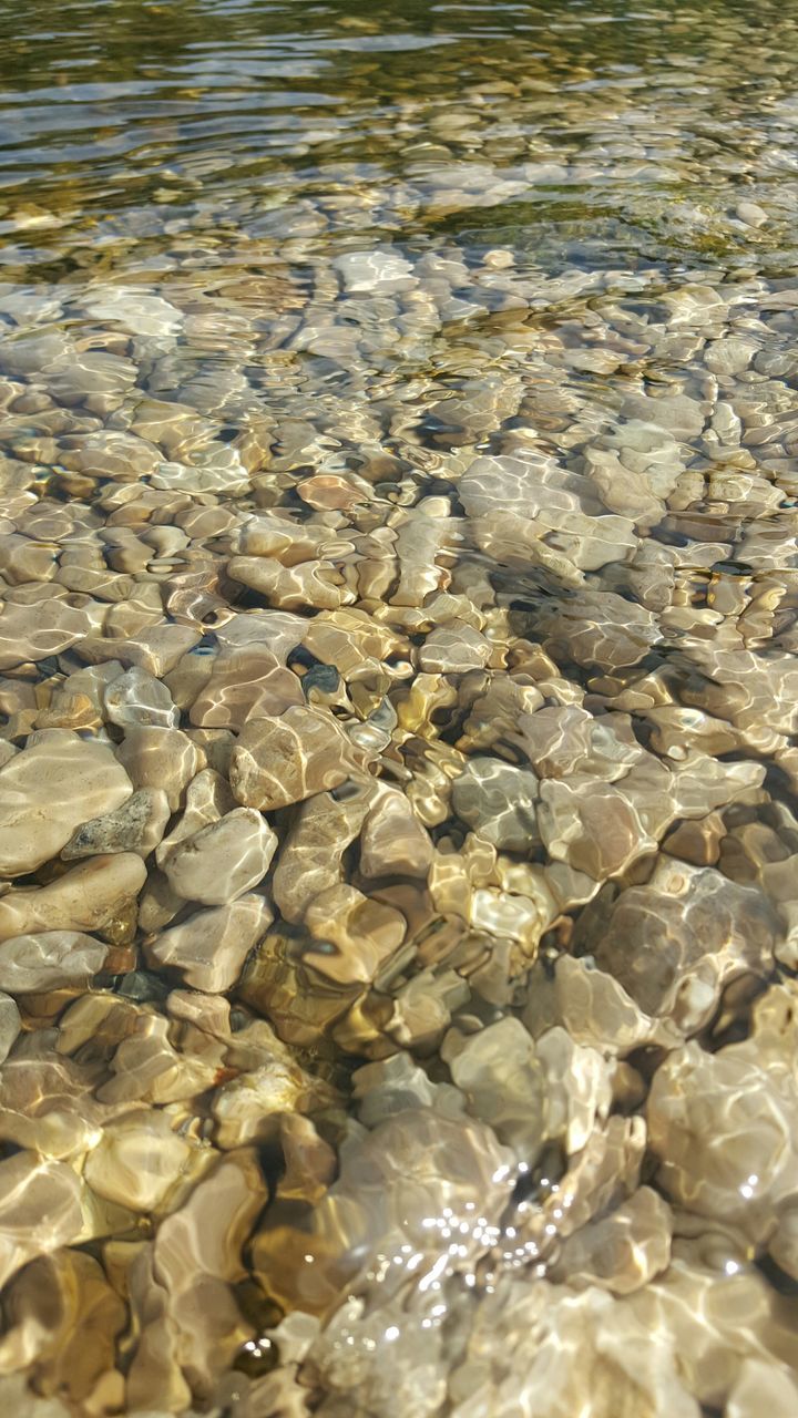 water, full frame, backgrounds, pebble, stone - object, nature, high angle view, abundance, rock - object, waterfront, day, rippled, outdoors, reflection, beach, sea, no people, sunlight, beauty in nature, tranquility