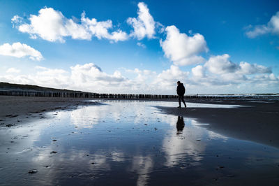 Silhouette man standing on beach against sky