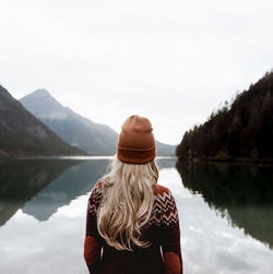 Rear view of woman looking at lake against sky