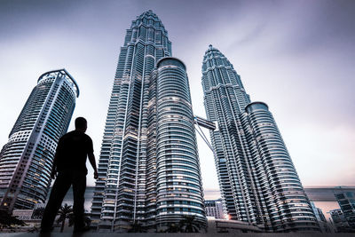 Low angle view of skyscrapers against cloudy sky