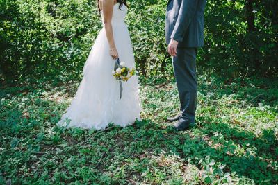 Low section of bride and groom standing on field