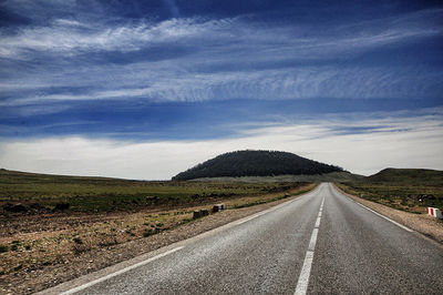 Country road against cloudy sky