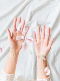 Woman's hands with pink flower petals. blurred photo in motion. spring, tenderness and fragility.