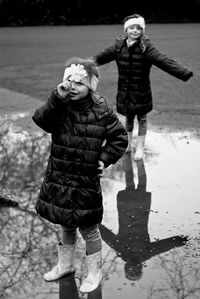 Portrait of cute siblings standing by puddle on road