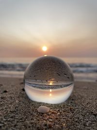 Close-up of pebble on beach against sky during sunset