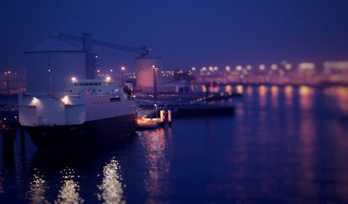 Boats in river with illuminates in distance