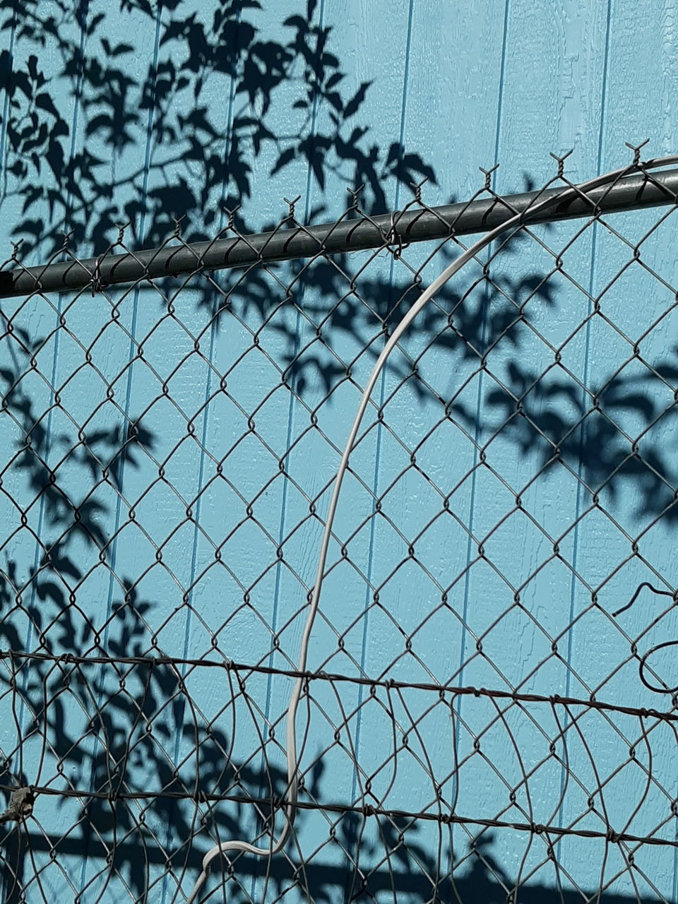 CLOSE-UP OF CHAINLINK FENCE AGAINST SKY SEEN THROUGH METAL