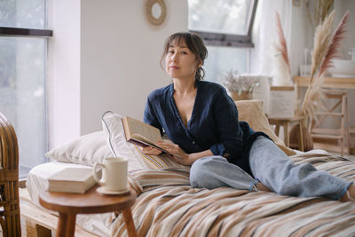 Woman reading book while sitting at home