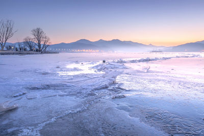 Scenic view of frozen lake against sky during sunset