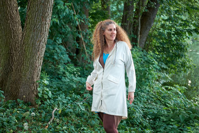 Woman standing by tree trunk in forest