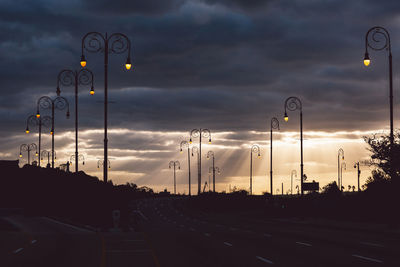 Cars on road against sky at sunset