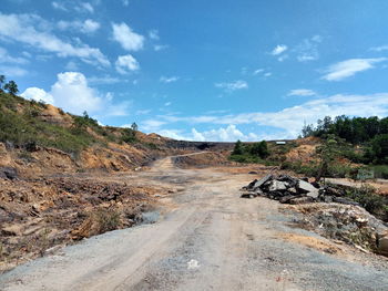 Dirt road on landscape against sky