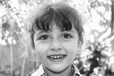 Close-up portrait of smiling girl against tree