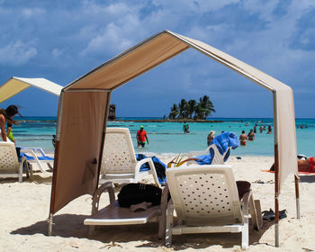 People sitting on chair at beach against sky