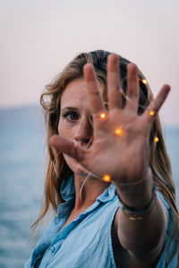 Portrait of woman with string light on hand