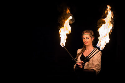 Portrait of female fire dancer at night