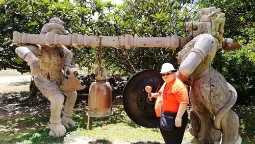 Statue of man standing by tree trunk