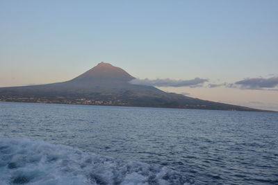 Scenic view of sea and mountains against clear blue sky