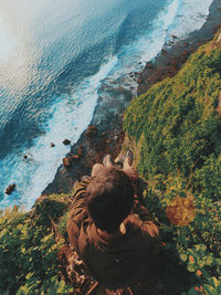 High angle view of people sitting on rock by sea