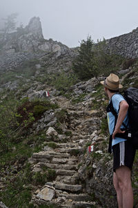 Rear view of person standing on rock by mountain